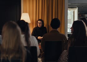 An author engaging with an audience during a book discussion in a cozy indoor setting.